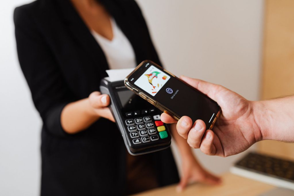 Customer making a contactless mobile payment using a smartphone tapped against a card reader, illustrating the quick and convenient repayment process for digital salary loans